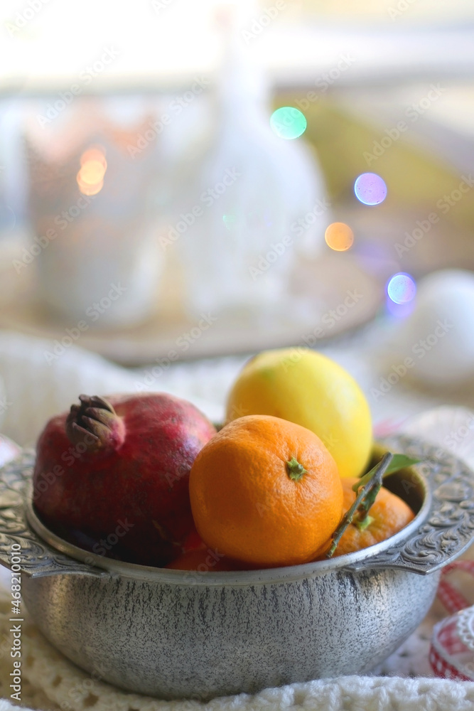 Silver bowl with various fruit, soft blanket and various Christmas decorations. Hygge at home. Selective focus. Silver bowl with various fruit, soft blanket and various Christmas decorations. Hygge at home. Selective focus.