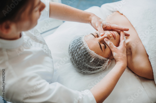 Close up of cosmetologist hands applying cleansing foam on client face. Concept of skincare, beauty. Spa alon photo