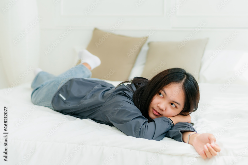 Portrait Asian cute long-haired teen wearing a gray long sleeve shirt Lay back and relax in bed in the bedroom happily. Portrait Asian cute long-haired teen wearing a gray long sleeve shirt Lay back and relax in bed in the bedroom happily.