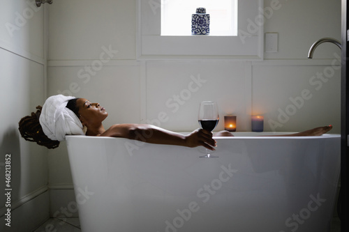 Black Woman taking relaxing bath with glass of wine photo