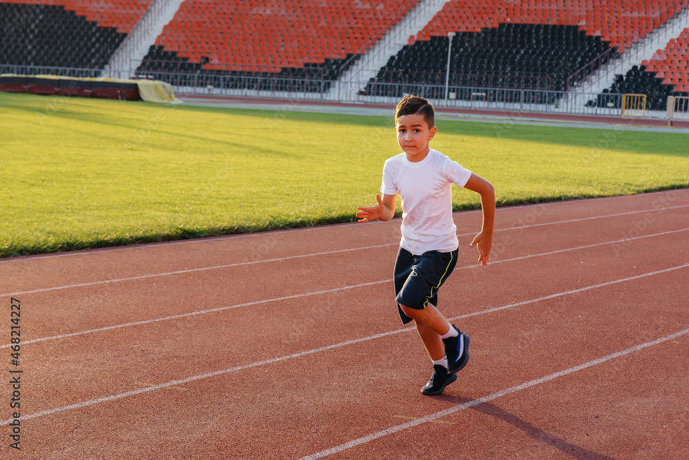 Obraz premium A large group of children, boys and girls, run and play sports at the stadium during sunset. A healthy lifestyle.
