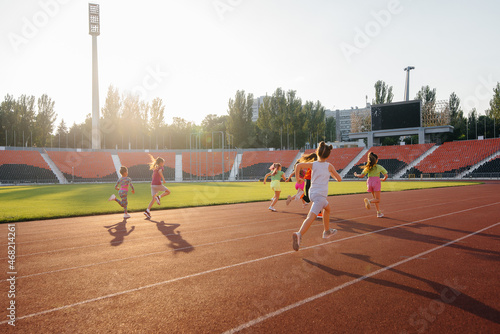 A large group of girls, run and play sports at the stadium during sunset. A healthy lifestyle.