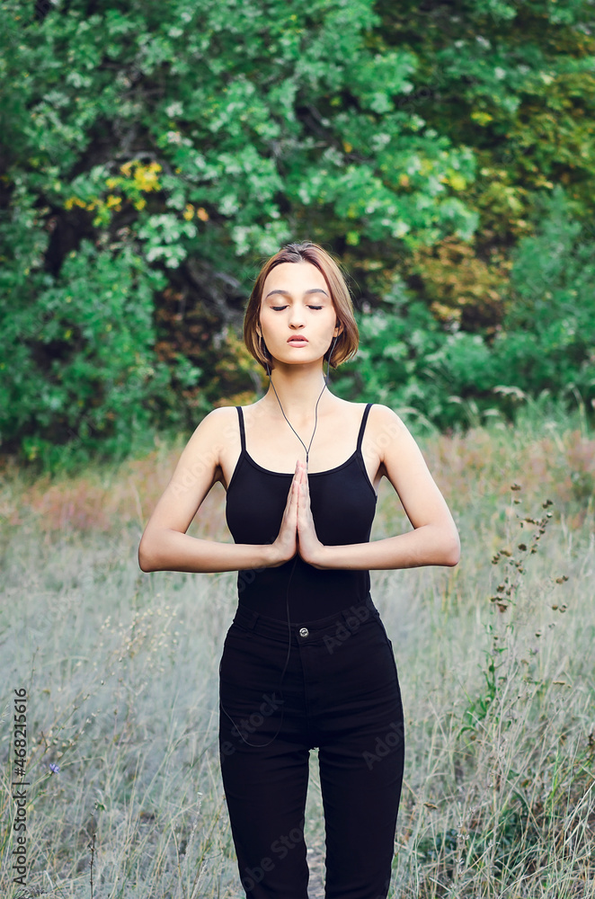 The girl is engaged in physical exercises in the park. Yoga classes outdoors. The girl is engaged in physical exercises in the park. Yoga classes outdoors.