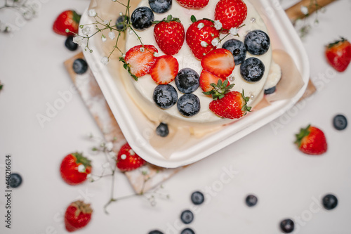 Beautiful white cake decorated with strawberries, blueberries and flowers