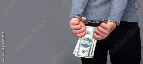 Woman in handcuffs holding money in her hands as a symbol of prostitution and illegal business. Copy space.