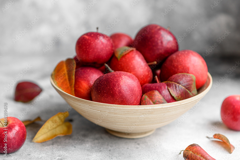 Beautiful fresh red apples with autumn leaves in a wooden vase Beautiful fresh red apples with autumn leaves in a wooden vase