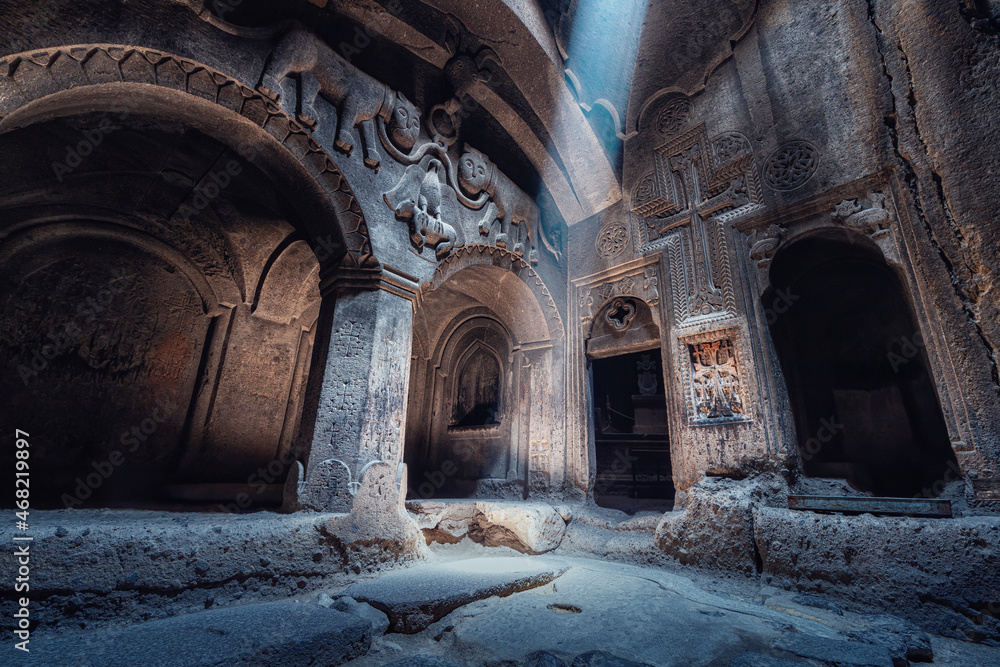 Interior of the famous Geghard Monastery and church carved into the rock. A ray of light illuminates an ancient bas-relief depicting lions in the hall