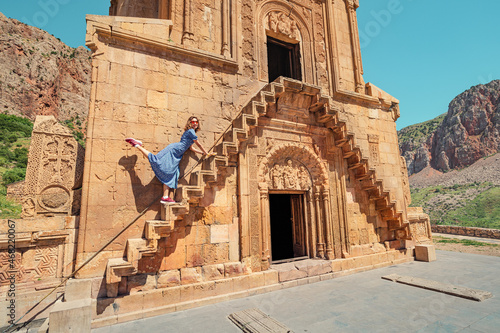 Happy woman climbs the narrow stairs to the second floor of the Noravank Monastery. Travel and tourism in Armenia concept photo