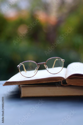 Vintage books and reading glasses in the garden. Selective focus.