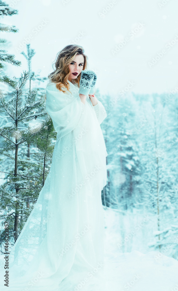 european beautiful blonde woman in a white dress in winter in the forest among trees and snow european beautiful blonde woman in a white dress in winter in the forest among trees and snow