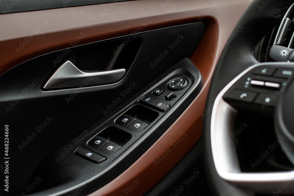 Close up view of button controlling window in modern car interior. Vehicle interior detail. Door handle with windows controls