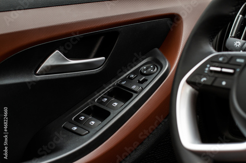 Close up view of button controlling window in modern car interior. Vehicle interior detail. Door handle with windows controls © Roman