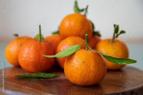 mandarine fruits with leaves lying on wooden surface. Selective focus on foreground fruit