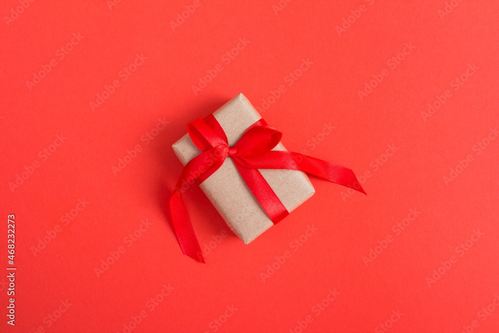 Gift box with tied red bow on the red background. Top view. Copy space. Gift box with tied red bow on the red background. Top view. Copy space.