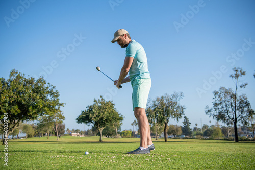 full length male golf player on professional course with green grass, golfing