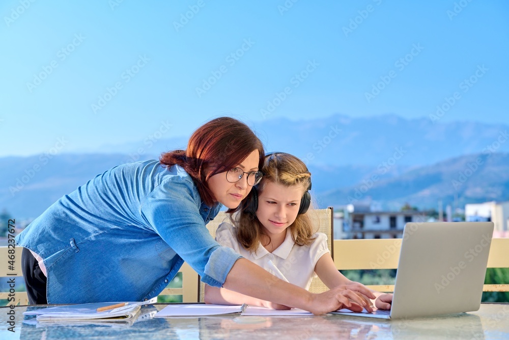 Mother helping her daughter to a schoolgirl with online studies