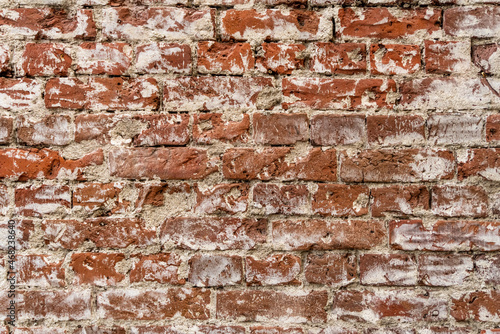 Old brick wall background with stains texture of white plaster. Closeup.