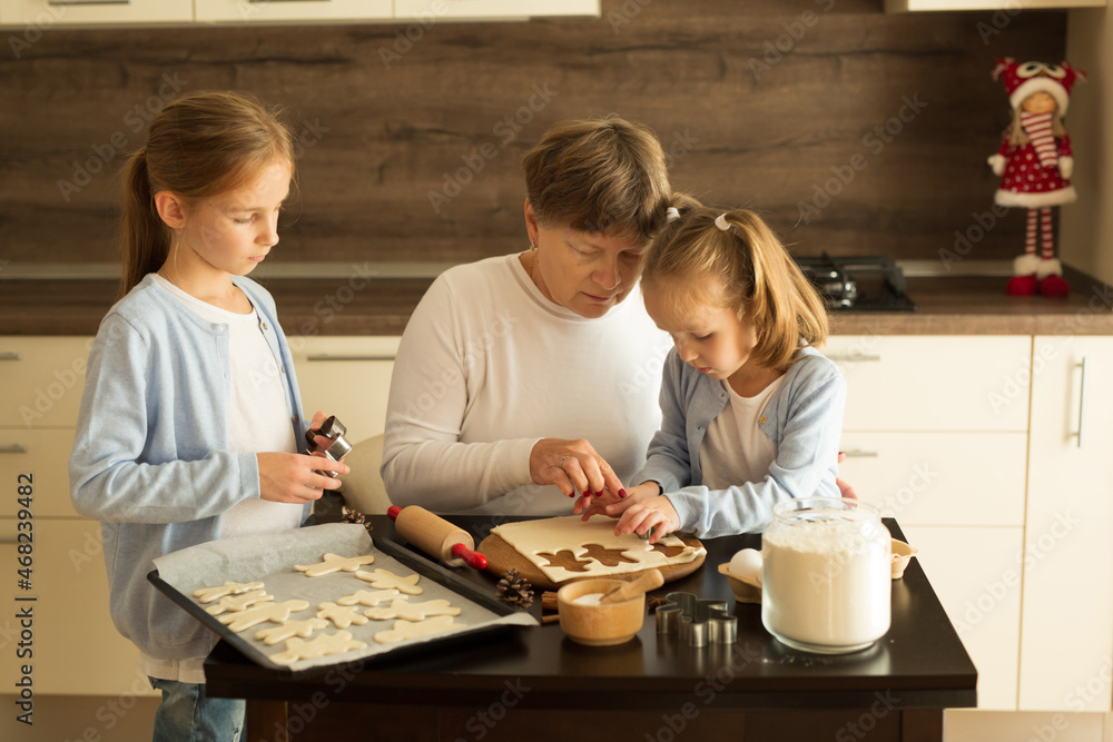 Girls with grandma are preparing Christmas cookies in the kitchen
