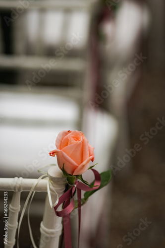 Decoration of single orange rose on white bed frame in focus with blurry background