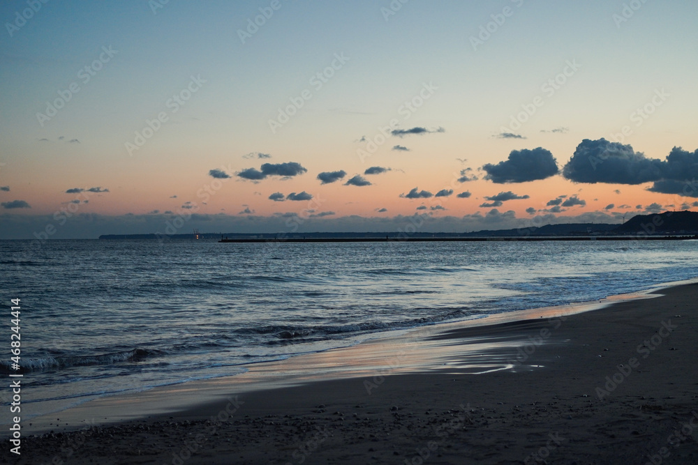View of the beach at sunset with orange sky and some clouds