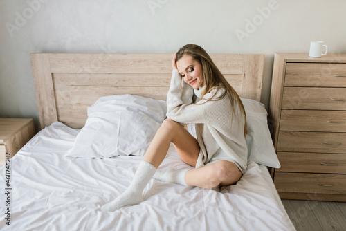 Attractive female with cup of coffee, smartphone and cakes in the bed © Ivan Zelenin