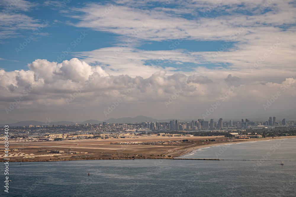 San Diego, California, USA - October 5, 2021: Dowtown skyline and Navy airport seen from Cabrillo National Monument under heavy blue cloudscape. Bay of Parcific Ocean up front.