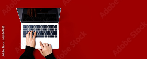 Person using a laptop computer on a solid color background