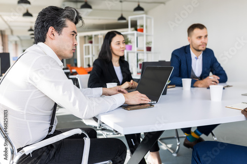 Group of young business people working and communicating while sitting at the office desk together with colleagues sitting. business meeting