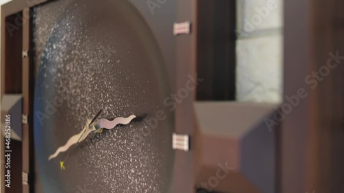 Wooden wall clock. On the white brick wall there is a beautiful large clock made of brown wood. The camera smoothly rises up gliding past them.