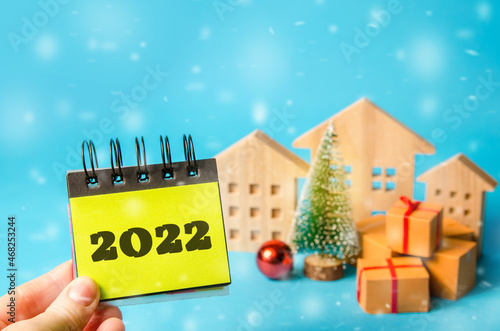 Notes with the word 2022, Christmas tree and miniature houses. New Year or Xmas winter holiday. Decoration, celebration. The concept of the beginning of the new year. Blue background