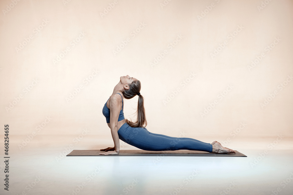 Young woman practising asanas, doing Cobra Pose exercises, stretch muscles. Healthy lifestyle, yoga lesson concept