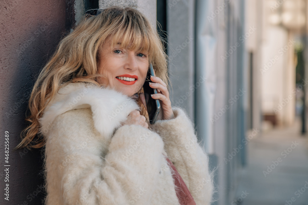 woman in coat talking on mobile phone in the street woman in coat talking on mobile phone in the street