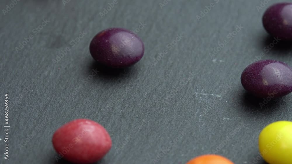 Colored fruit sweets scatter on a black background, colored marco sweets Colored fruit sweets scatter on a black background, colored marco sweets