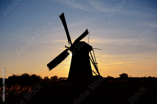 Colorful sunset at a traditional, Dutch windmill near a pond Focus on windmill