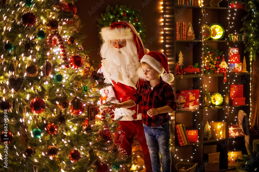 Santa Claus decorating Christmas tree with little boy assistant at home. New Year, Happy childhood Santa Claus decorating Christmas tree with little boy assistant at home. New Year, Happy childhood
