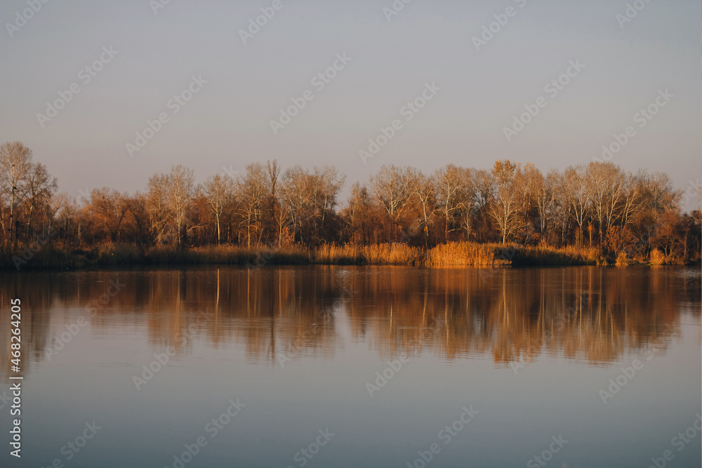 Vivid autumn sunset. Autumn landscape of sunset over river with shining grass on shore. Scenic nature at bright evening with colorful sky Vivid autumn sunset. Autumn landscape of sunset over river with shining grass on shore. Scenic nature at bright evening with colorful sky