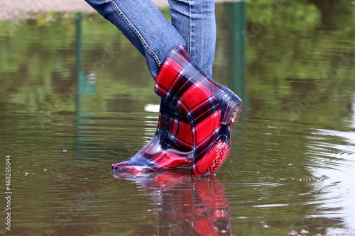 Human feet in rubber boots in Puddle of water