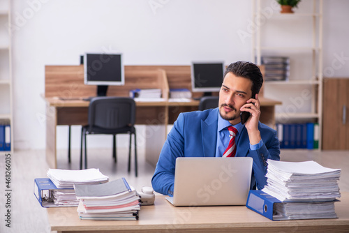 Young male employee unhappy with excessive work at workplace