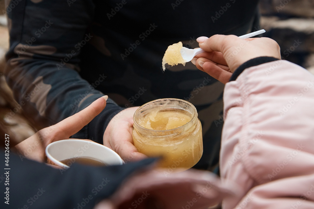 a man holding a spoon with honey in hand, close-up, a jar of honey, blurred background a man holding a spoon with honey in hand, close-up, a jar of honey, blurred background