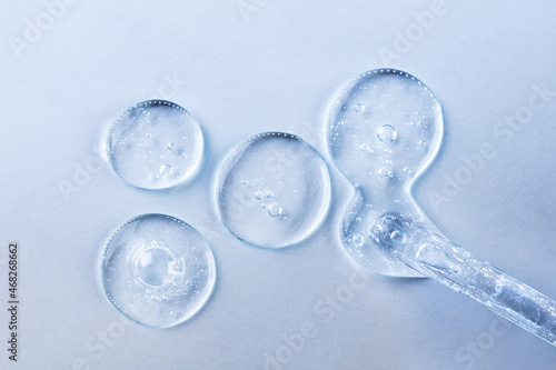Transparent gel or serum pipette with drops on light background. Cosmetics concept with fluid. © lisannart