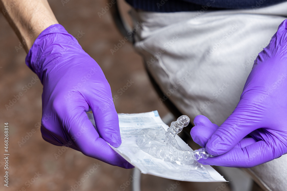 Man holding transparent aligner and its package. Invisalign orthodontics concept