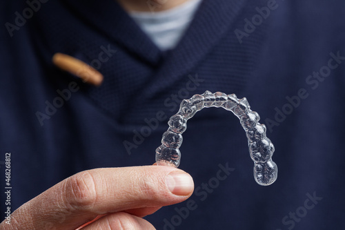 Man holding one transparent aligner. Invisalign orthodontics concept