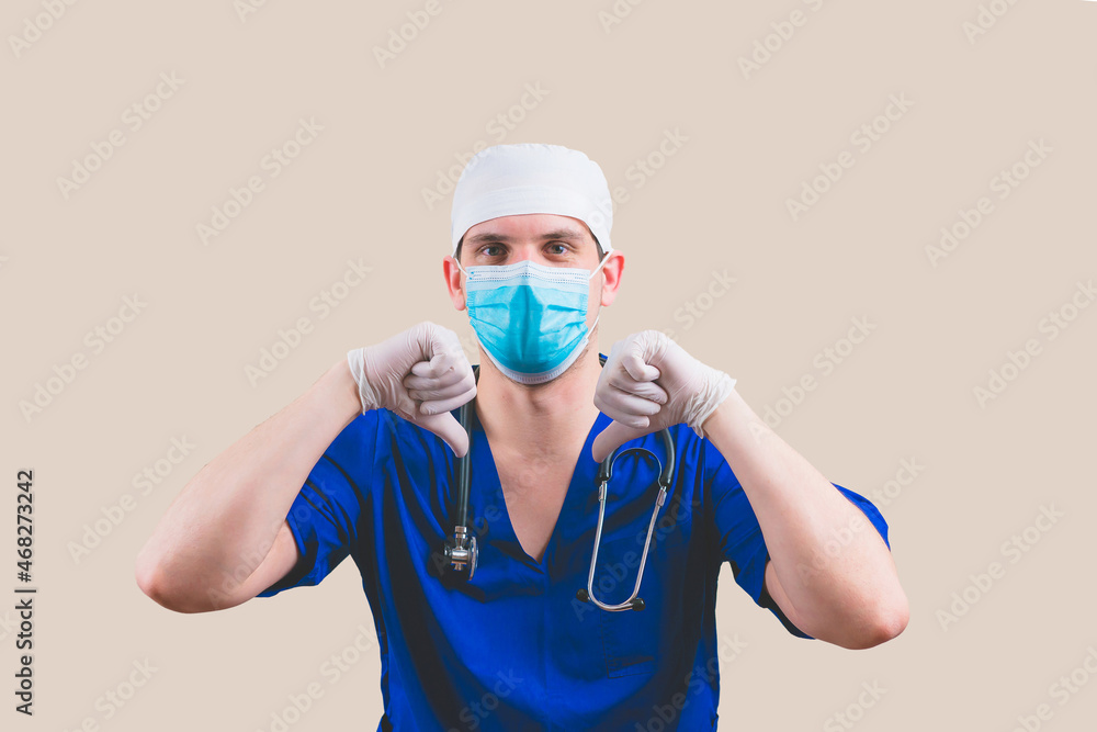 Doctor with thumbs down in blue surgeon suit and glasses with stethoscope on the yellow background isolated Doctor with thumbs down in blue surgeon suit and glasses with stethoscope on the yellow background isolated