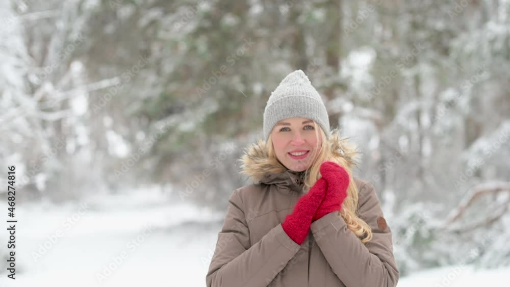 Portrait of a young happy girl in outerwear looks at the camera and smiles in a beautiful snowy park. Winter holidays Portrait of a young happy girl in outerwear looks at the camera and smiles in a beautiful snowy park. Winter holidays