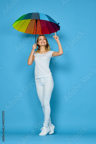 fashionable woman with umbrella rainbow colors posing blue background