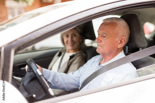 Elderly man and woman driving a car in the city. Man driving a car © JackF