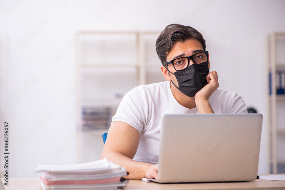 Young male student employee working at workplace during pandemic Young male student employee working at workplace during pandemic