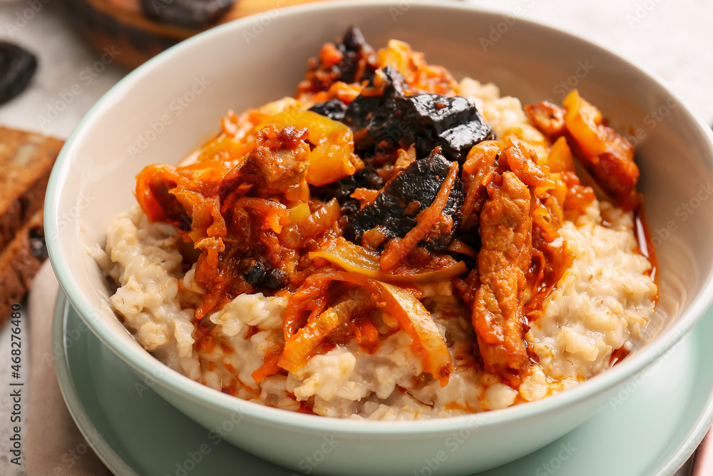 Bowl with tasty oatmeal, gravy with beef and prunes on table, closeup Bowl with tasty oatmeal, gravy with beef and prunes on table, closeup
