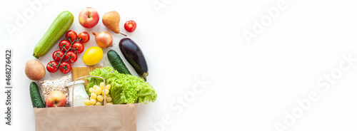 Paper grocery bag with fresh vegetables, fruits, pasta, oatmeal and milk on white table. Food shopping, delivery, diet concept. Healthy food background. Flat lay, top view, copy space, banner.