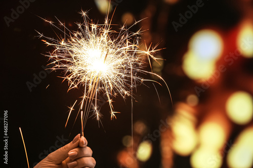 Female hand with beautiful sparklers against blurred lights